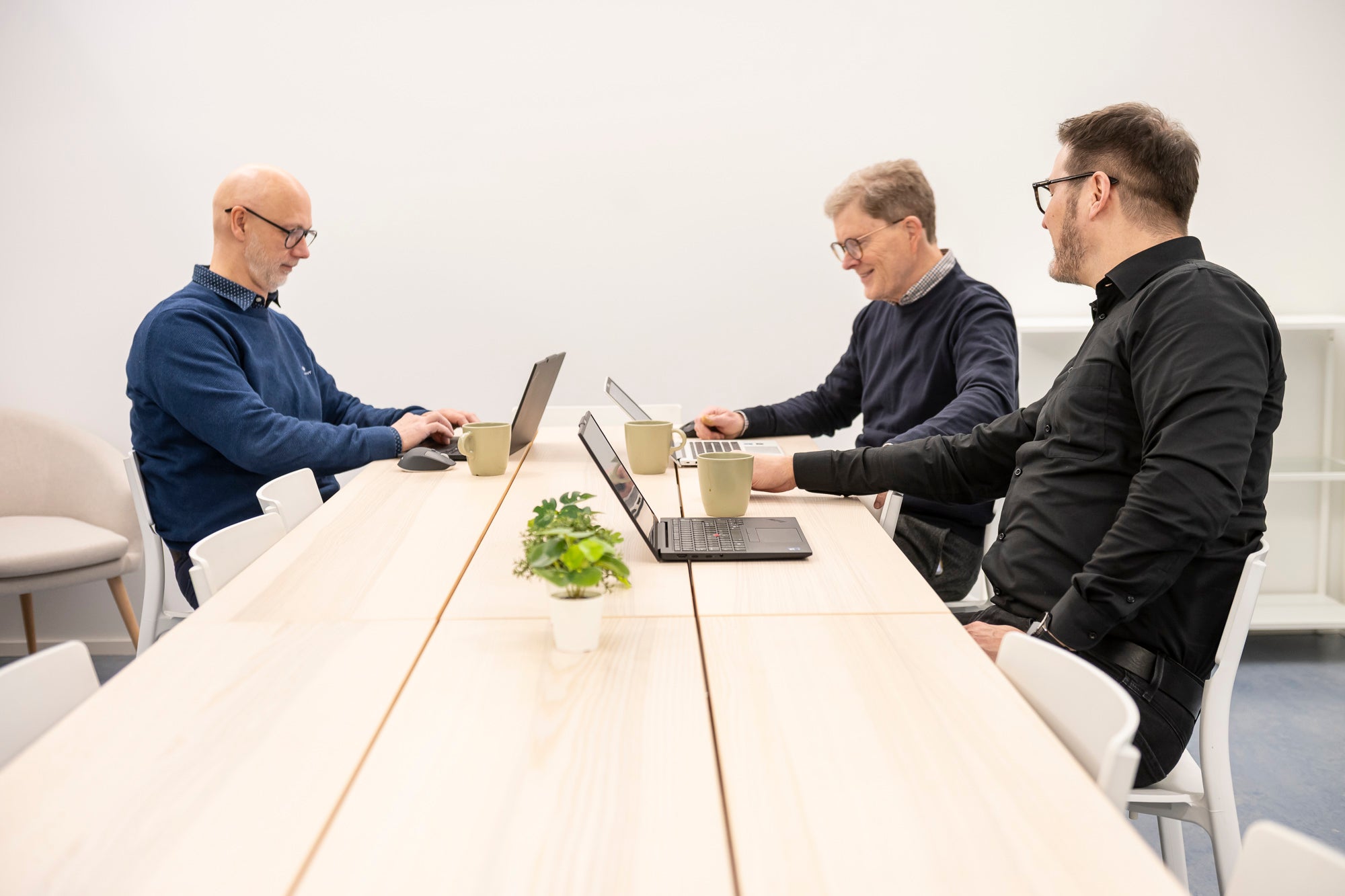 Kolme HT-Prokonin asiantuntijaa kokoustamassa kannettavien tietokoneiden ääressä.