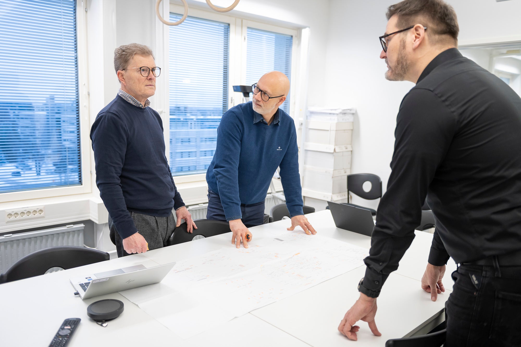 Kolme HT-Prokonin työntekijää huomioliiveissä ja suojakypärissä rakennustyömaan sisätiloissa.